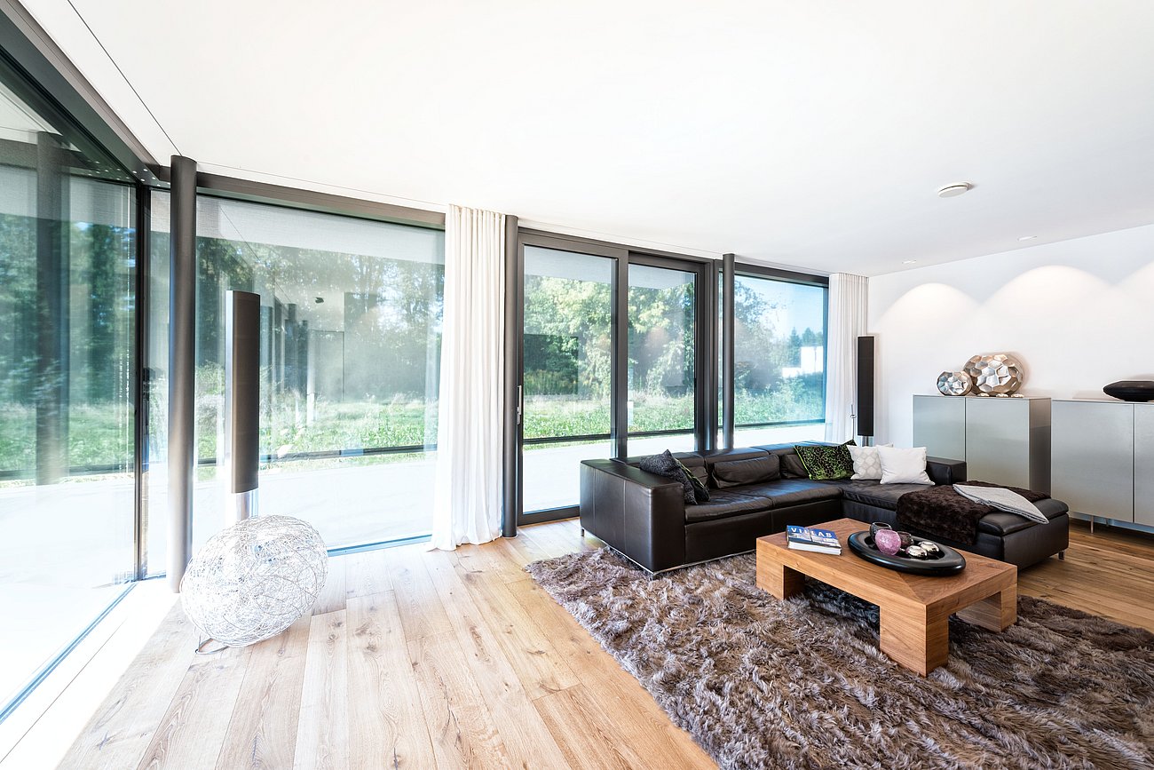 Innenansicht eines modern eingerichteten Wohnraums mit großer Fensterfront und halb geschlossenen Textilscreens