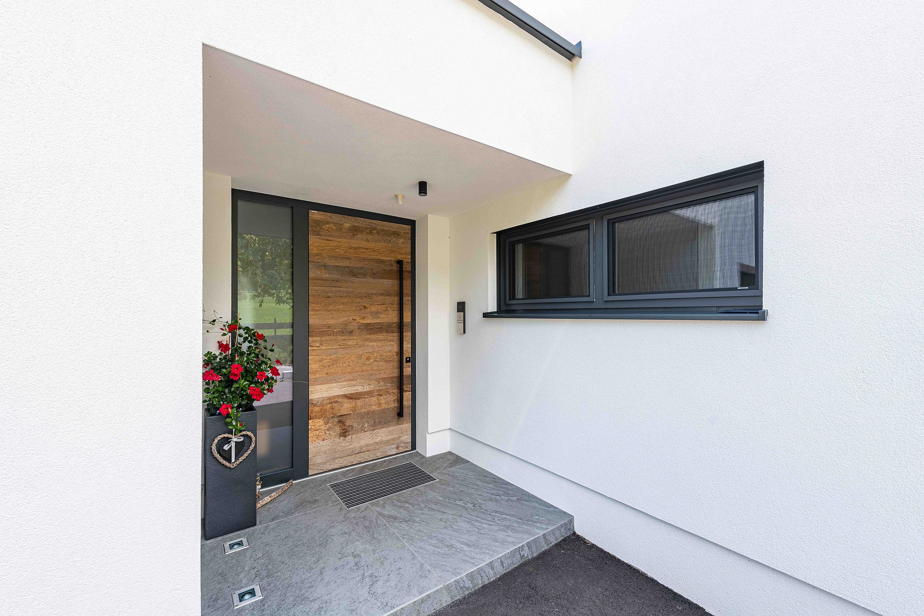 Außenansicht eines Eingangsbereichs mit Holz-Haustür und verglastem Seitenteil